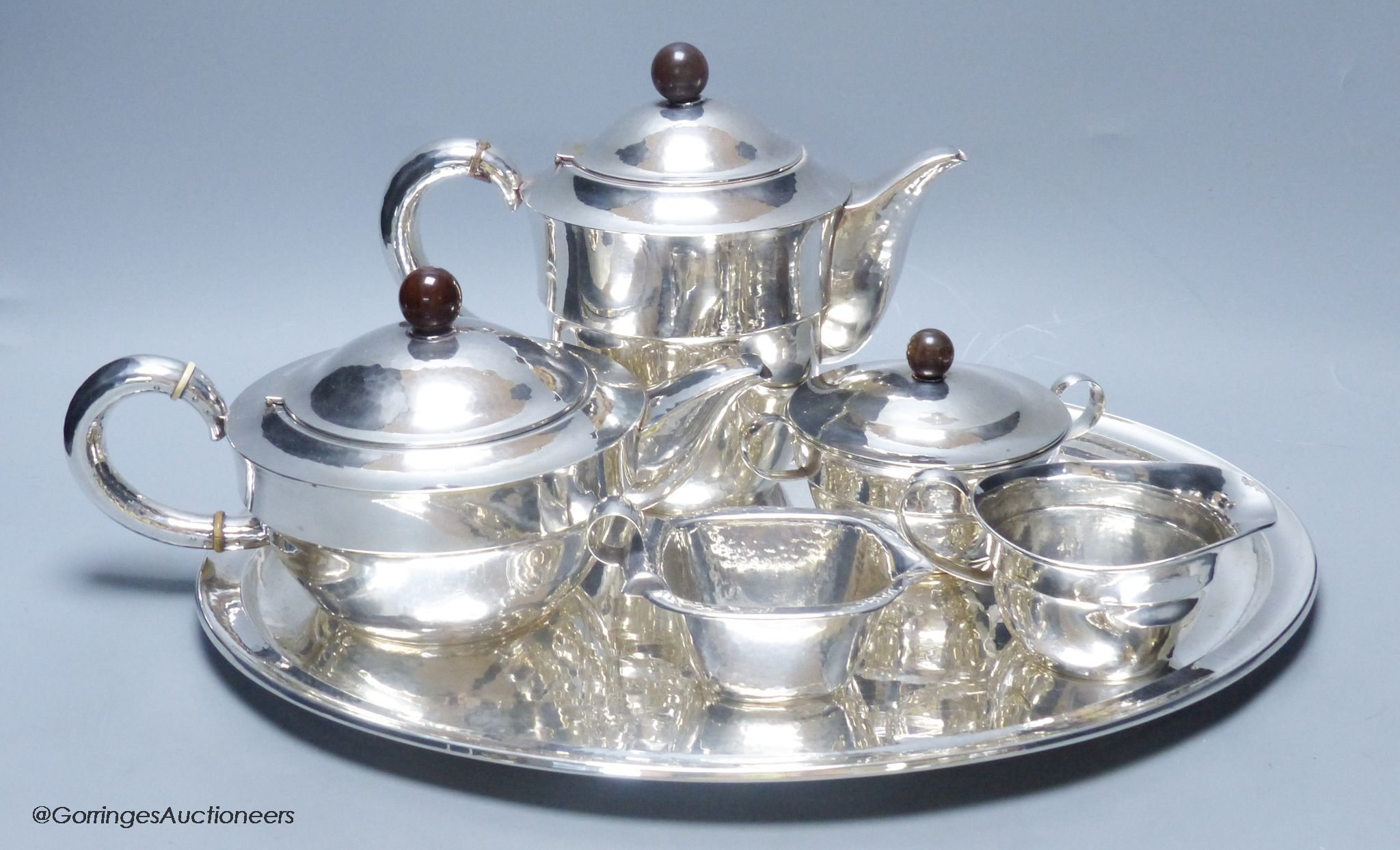 An early 20th century German planished 830s white metal six piece tea and coffee service comprising oval tray, teapot, coffee pot, creamer and milk jug, by M.H. Wilkens & Sohne